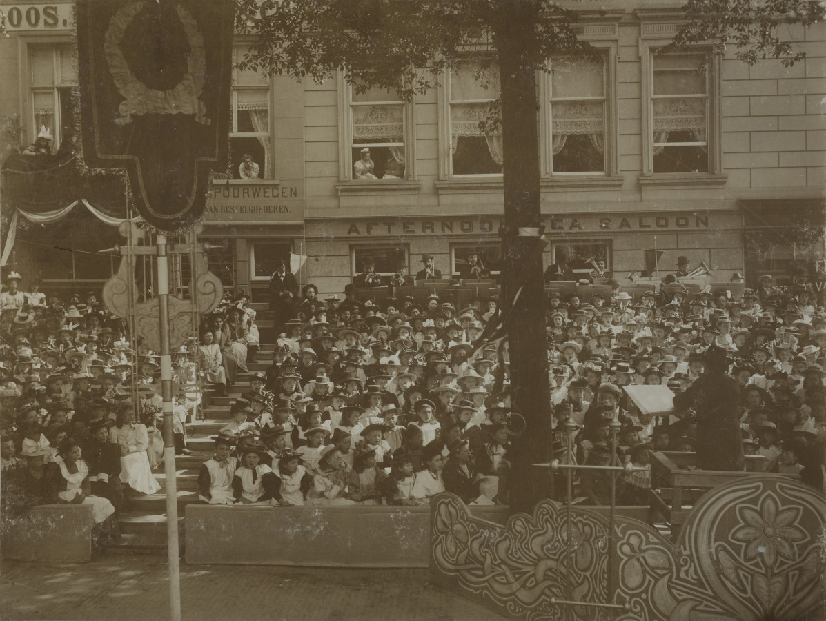 G. C. Bunk (bottom right) conducts during the visit of the queens a children's choir at the van Hogendorpsplein (Stadsarchief Rotterdam)